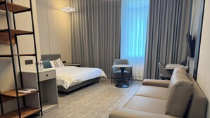 A hotel room with a bed, a sofa, a small table, and a chair. - Wind Rose hotel (Almaty)