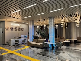 Un moderno vestíbulo de hotel con una recepción, zona de estar e iluminación decorativa.
