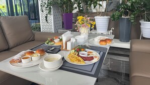 A dining area with a table set for breakfast, including plates of food, bread, and beverages. - Wind Rose hotel (Almaty)