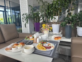 Un comedor con una mesa dispuesta para el desayuno, que incluye platos de comida, pan y bebidas.