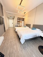 Habitación de hotel con dos camas, un armario, un escritorio y baño.