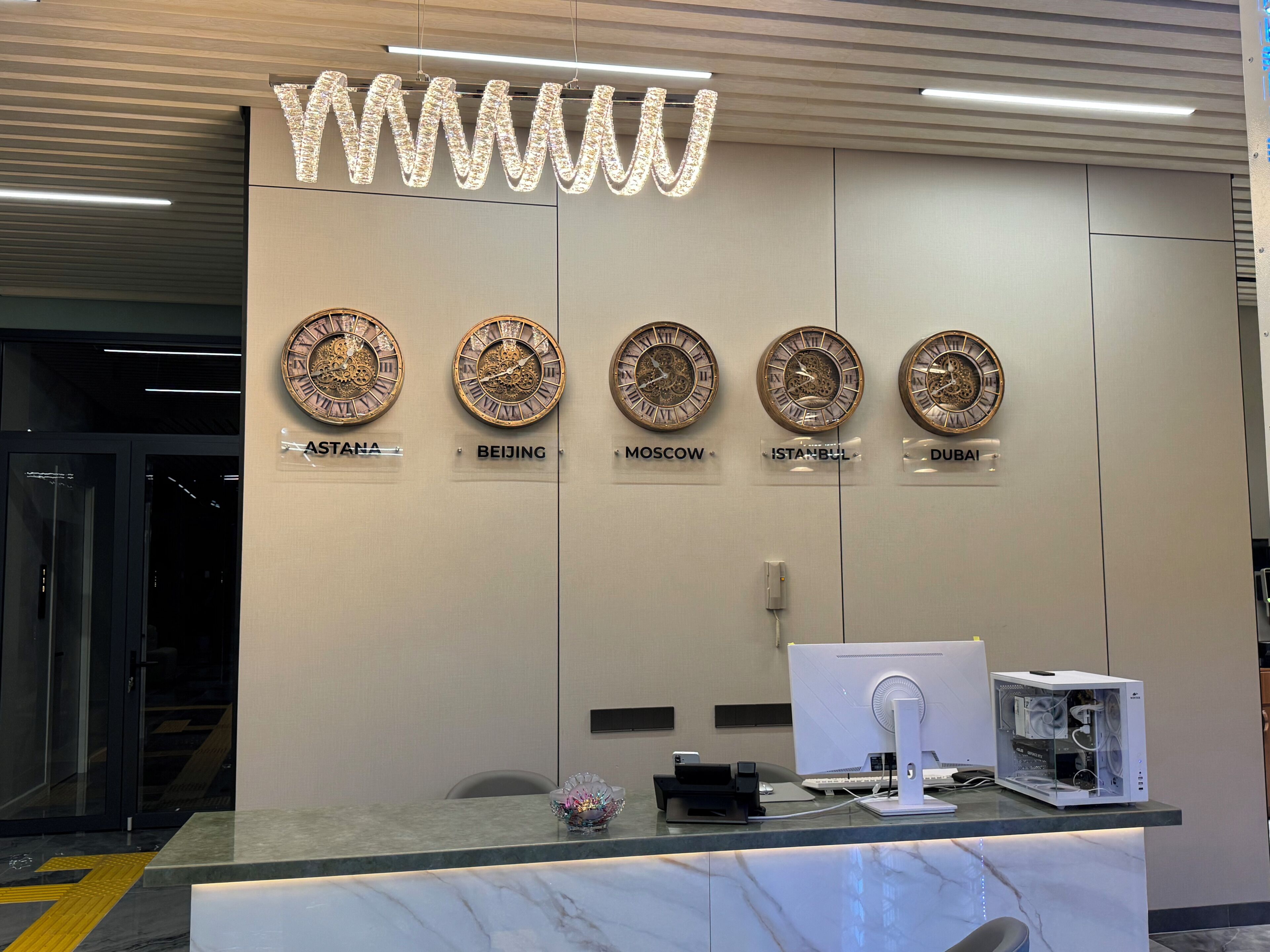 A reception desk with clocks indicating time in various cities, a modern fan, and a glass display case.