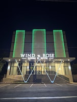 The exterior of the Wind & Rose Oonaq Hotel with illuminated signage and a modern architectural design.
