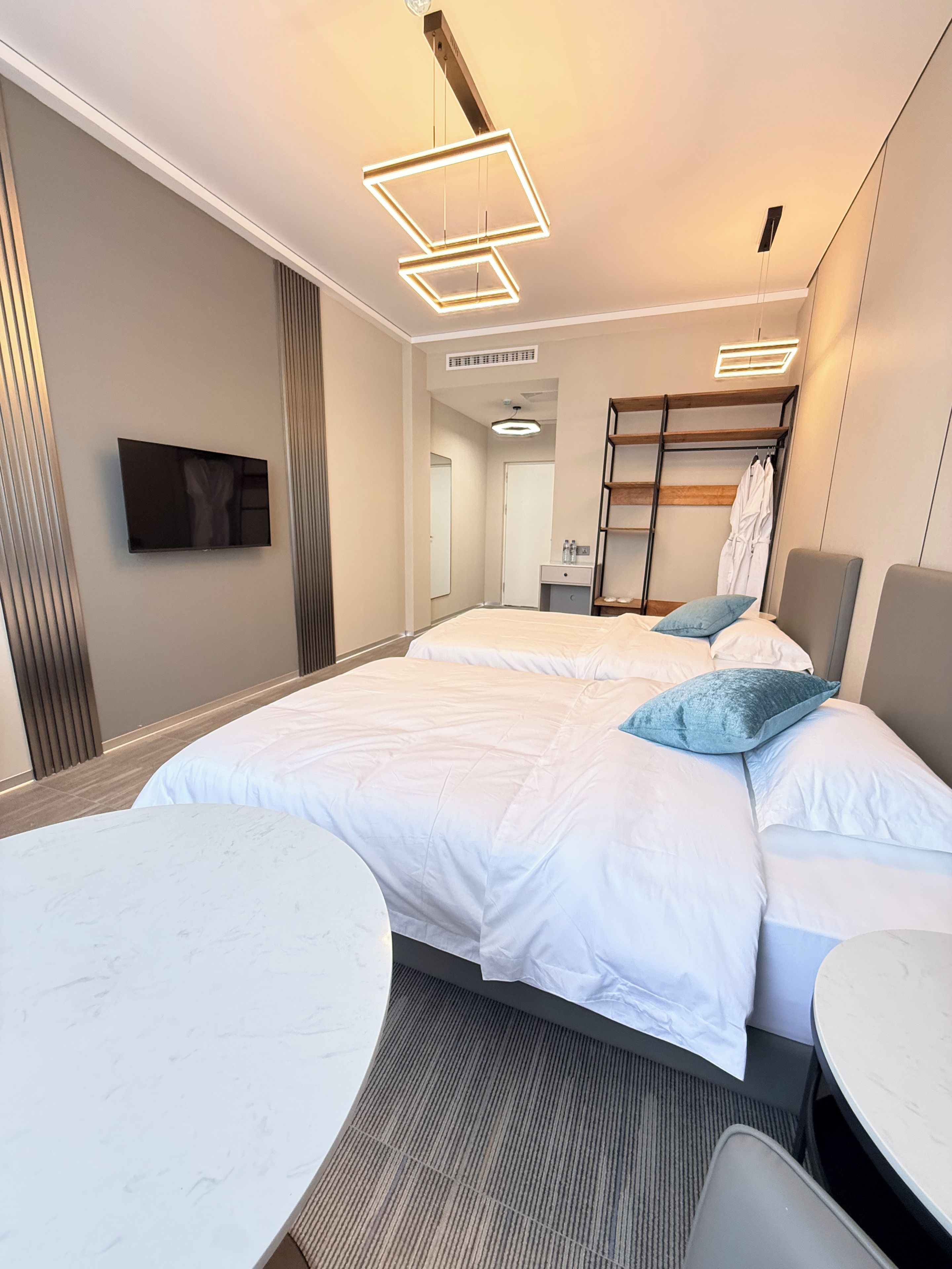 Habitación de hotel con una cama grande, una mesa redonda, un televisor montado en la pared y una cama litera con escalera.