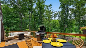 Eine Terrasse im Freien mit Esstisch, Stühlen, Grill und einer Sitzecke.