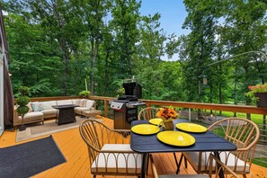 Une terrasse extérieure avec une table à manger, des chaises, un barbecue et un canapé.