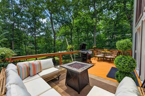Une terrasse équipée d’un barbecue, de meubles pour s’asseoir à l’extérieur et d’un foyer.