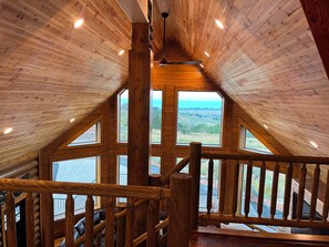 A wooden interior with a sloped ceiling, large windows, and a wooden railing. - NEW Bear Lake Cabin in Garden City (Garden City)
