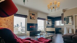 Ett modernt vardagsrum med en stor TV som visar Netflix-logotypen, ett soffbord i glas och en röd soffa.