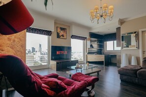A modern living room with a large TV displaying the Netflix logo, a glass coffee table, and a red sofa. - Luxury Duplex With Jacuzzi, Stunning Views (St. Julian's)