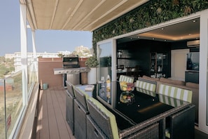 A balcony with a grill, dining table, and chairs, overlooking a residential area. - Luxury Duplex With Jacuzzi, Stunning Views (St. Julian's)