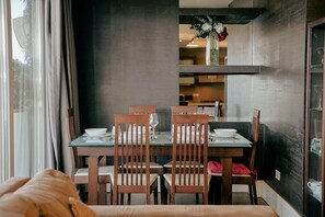 A dining area with a table set for four, wooden chairs, and a vase with flowers on the wall. - Luxury Duplex With Jacuzzi, Stunning Views (St. Julian's)