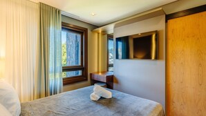 A hotel room with a bed, a television, and a window with curtains. - Beautiful Apartment in Gramado Dms0304 (Gramado)