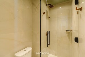 Een moderne badkamer met een douche in een glazen cabine, een toilet en een wastafel.
