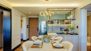 A modern kitchen with a central island, built-in appliances, and a dining area with a table set for four. - Apt w/ Balcony, Fireplace & View in Center Dms0107 (Gramado)