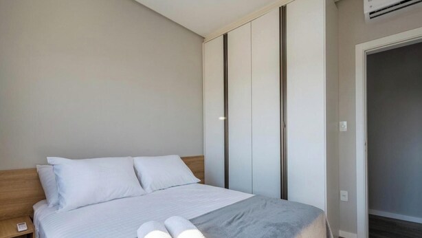 Une chambre à coucher comprenant un lit, une table de chevet, une armoire et un appareil de climatisation.