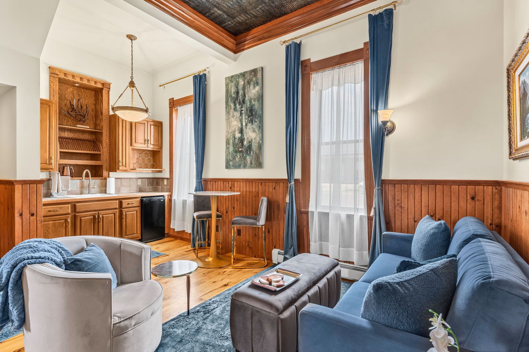 Sala de estar com sofá, poltrona e mesa de centro. Há uma cozinha com armários de madeira e pia.