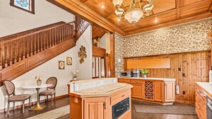 A wooden interior with a staircase, a dining area, and a kitchen with wooden cabinets and a wine rack.