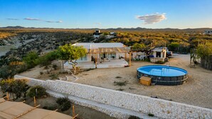 Ein Haus mit Pool, umgeben von einer Steinmauer und Wüstenpflanzen.