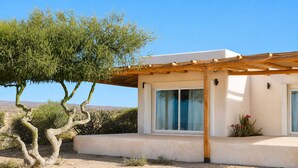 Ein modernes Haus mit einer Pergola, großen Fenstern und einer Wüstenlandschaft.
