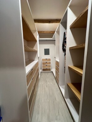 Ein schmaler Durchgangsschrank mit Holzböden und Schubladen, ein Holzboden und ein kleines, an der Wand befestigtes Element.