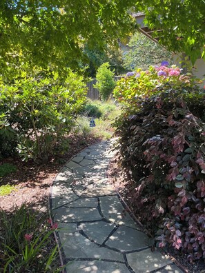 A stone pathway surrounded by lush greenery and flowering plants. - Beautiful, Private Studio on Panoramic Hwy in Mill Valley above Muir Woods (Mill Valley)