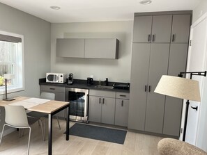 Eine moderne Küche mit grauen Schränken, einer Mikrowelle, einer Kaffeemaschine und einem Essbereich mit Tisch und Stühlen.