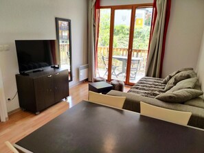 A modern living room with a flat-screen TV, a sofa, a coffee table, and a sliding glass door leading to an outdoor patio. - 200m from ski slopes, 2nd floor, swimming pool, balcony, tv, ski locker, 30m², Les Orres (Les Orres)