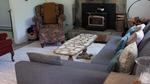 A living room with a fireplace, a patterned armchair, a sofa, and a coffee table.