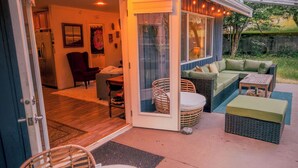 An outdoor patio area with a covered seating area, a wicker chair, and a sofa.