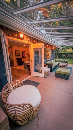 An outdoor patio area with a covered seating area, a wicker chair, and a sofa.