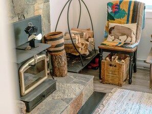 A fireplace with a vintage radio, a woven basket, and a chair with a colorful cushion.