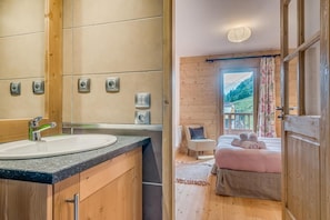A modern bathroom with a large mirror, a sink, and multiple electrical outlets. The room features wooden walls and a large window with a view of a mountainous landscape. - 50m from ski slopes, 2nd floor, balcony, parking, tv, ski locker, 64m², Champagny-en-Vanoise (Champagny-en-Vanoise)