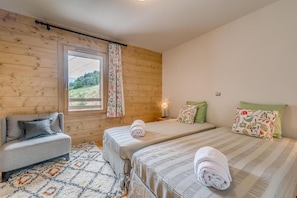 A room with two beds, a sofa, a window with curtains, and a lamp. - 50m from ski slopes, 2nd floor, balcony, parking, tv, ski locker, 64m², Champagny-en-Vanoise (Champagny-en-Vanoise)