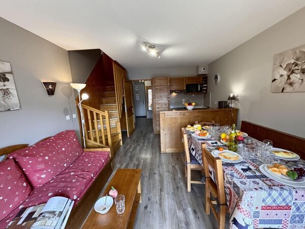 A compact living space with a dining area, a sofa, a wooden staircase, and a kitchen in the background. - 50m from ski slopes, 4th floor, swimming pool, balcony, ski locker, 50m², Vars (Vars)