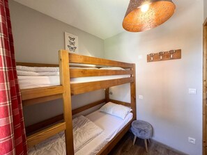 A bunk bed room with a wooden headboard, a small stool, a wall-mounted hookboard, and a ceiling light fixture. - 50m from ski slopes, 4th floor, swimming pool, balcony, ski locker, 50m², Vars (Vars)