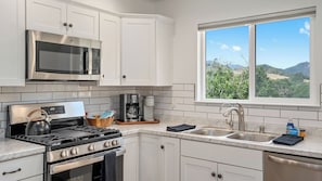 A modern kitchen with stainless steel appliances, a gas stove, a kettle, and a coffee maker. - Stampede Loft at The 8 Mile by Avantstay Private Porch + Full Kitchen Ranch Acreage + Trails (Santa Margarita)