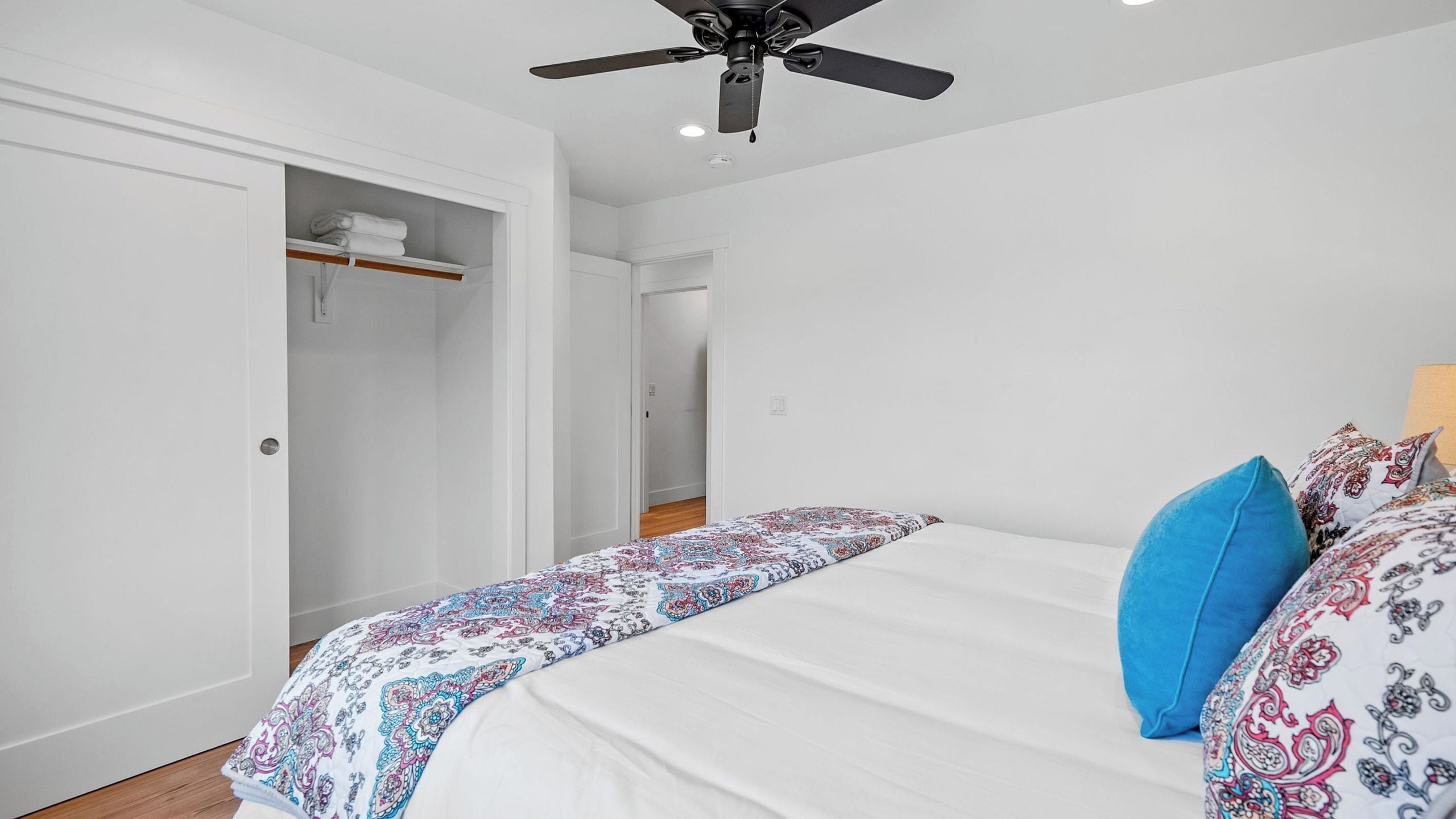 A bedroom with a bed, a ceiling fan, and a wardrobe.