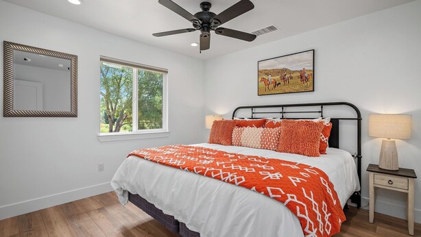 A bedroom with a bed, a ceiling fan, a window, a nightstand, a lamp, and a framed picture on the wall. - Stampede Loft at The 8 Mile by Avantstay Private Porch + Full Kitchen Ranch Acreage + Trails (Santa Margarita)
