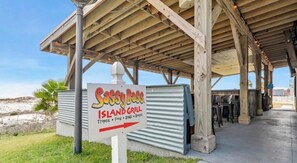 Ein Restaurant direkt am Strand, genannt 'Sassy Pass Island Grill', mit überdachter Außenbestuhlung.