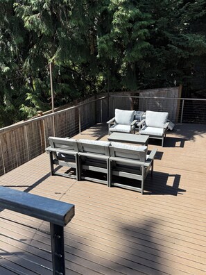 Eine Terrass mit Holzboden, Metallgeländern und zwei weißen Loungesesseln.