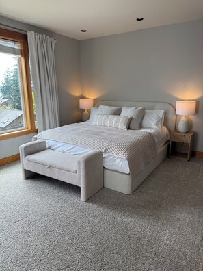 Ein Schlafzimmer mit einem großen Bett, zwei Nachttischen und einem Fenster mit Vorhängen.