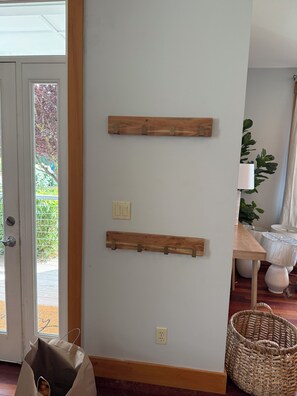 A room with a wooden wall-mounted shelf, a door with a view to the outside, and a wicker basket on the floor. - Charming Indianola home, Walk to Beach, & Pier (Indianola)