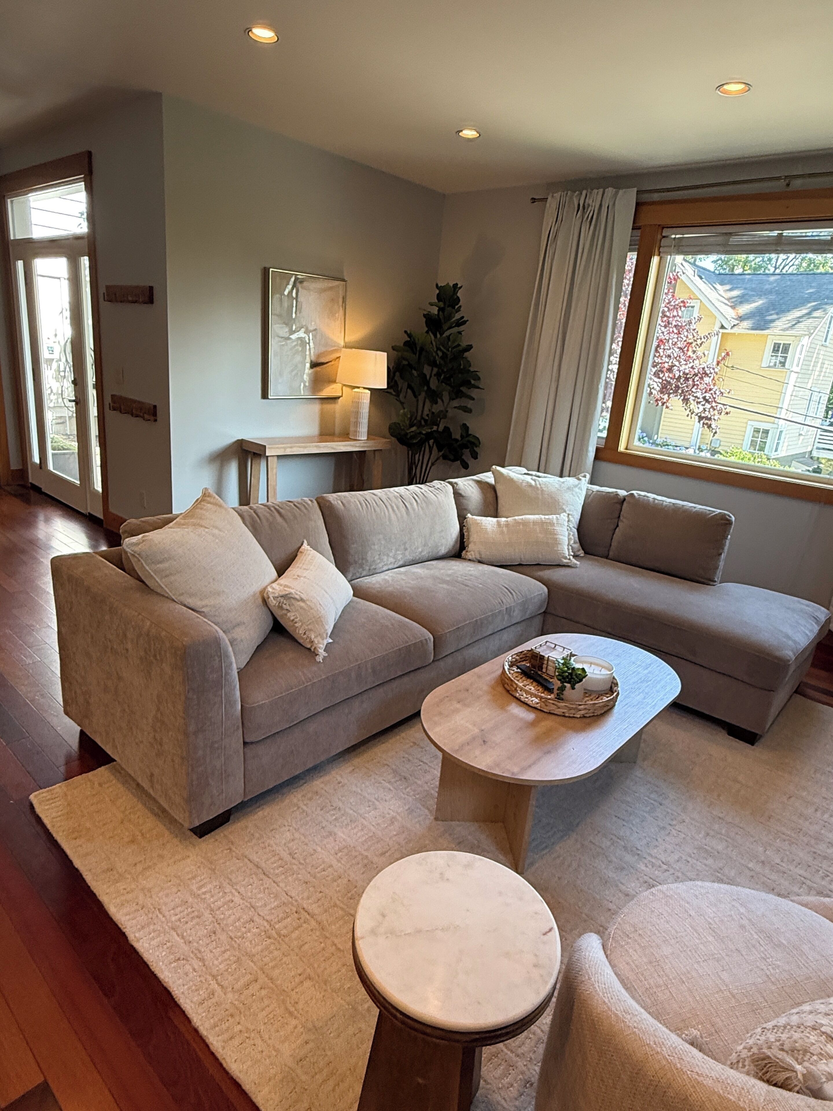 Ein modernes Wohnzimmer mit einer Eckcouch, einem runden Couchtisch und einem kleinen Beistelltisch.