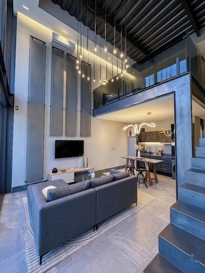 A modern interior with a sofa, dining table, kitchen, and staircase.
