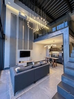 A modern interior with a sofa, dining table, kitchen, and staircase.