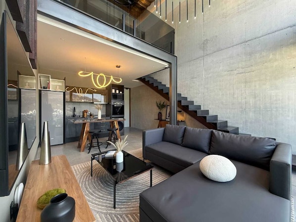 A modern interior with a living area, kitchen, and staircase.