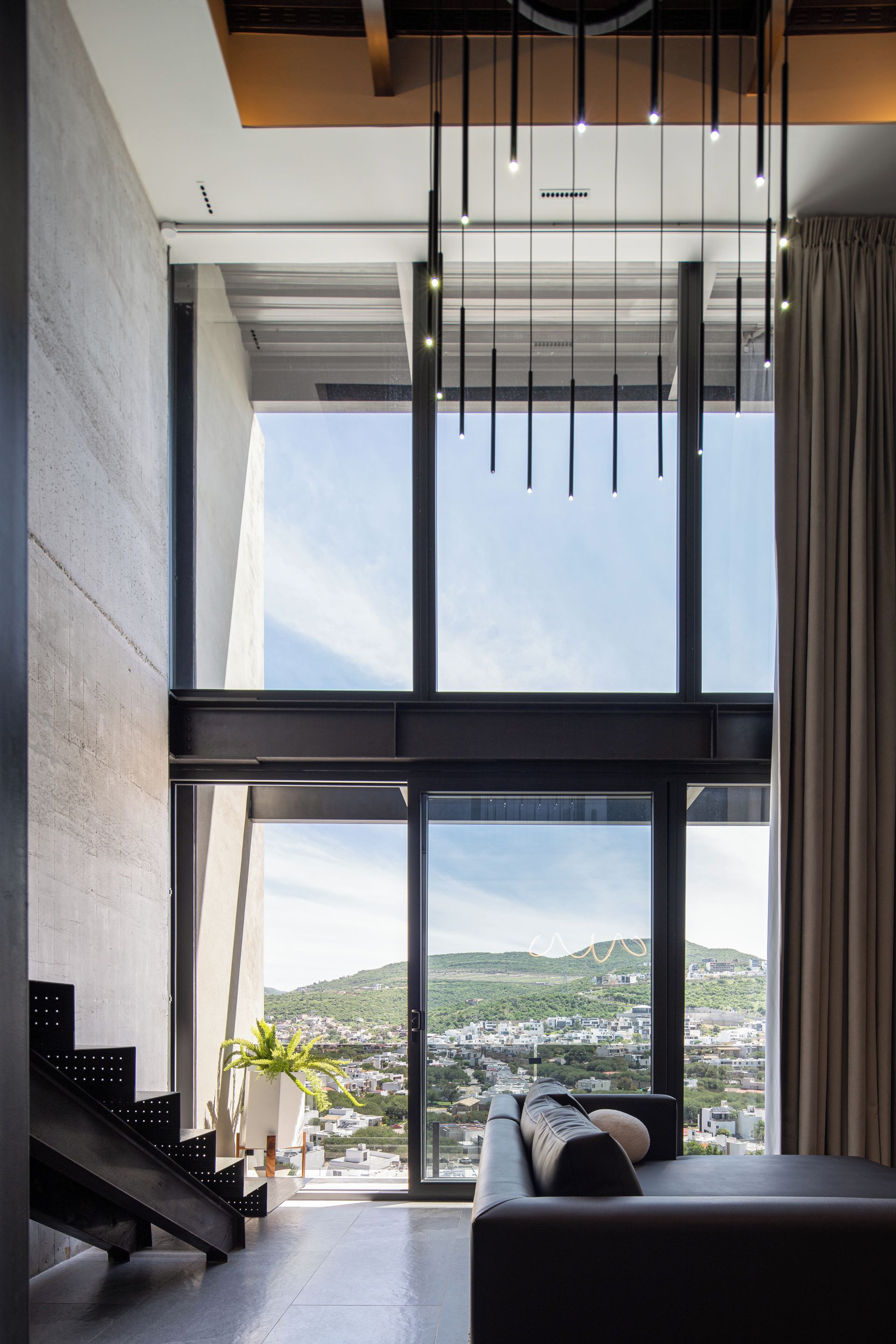 A modern interior with a large window, a sofa, and a staircase.