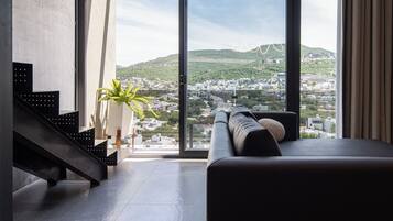 A modern interior with a large window, a sofa, and a staircase.
