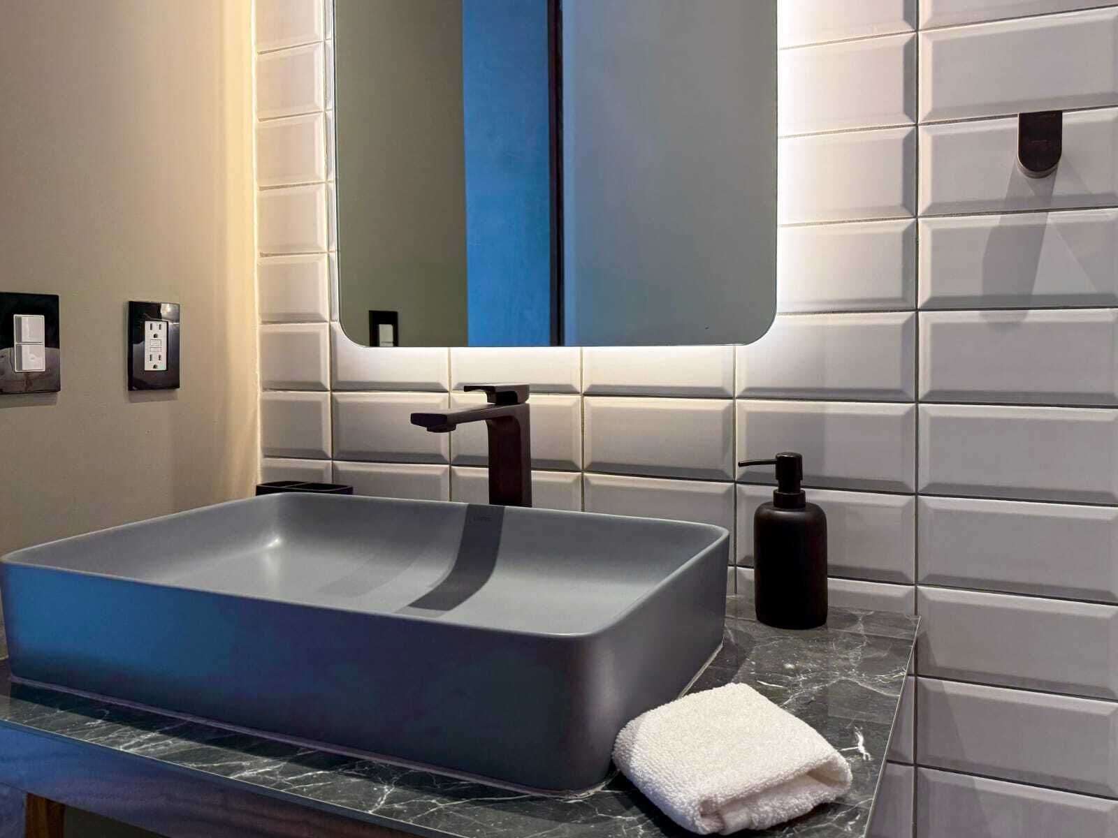 Une salle de bain moderne avec un lavabo rectangulaire, un miroir et une serviette posée sur le comptoir.